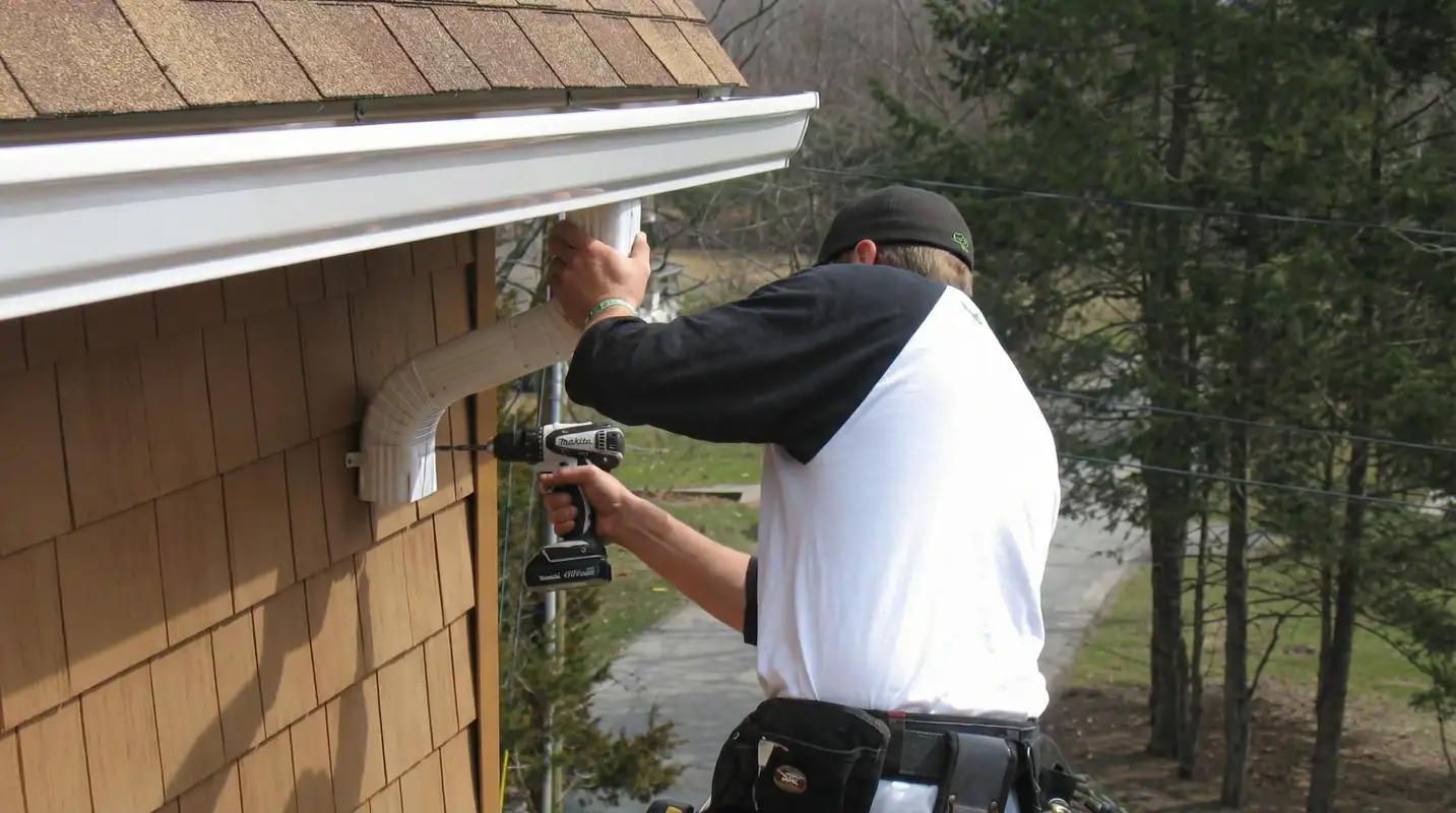 Professional contractor installing tan vinyl siding panels on a residential home exterior in Grand Rapids, Mi